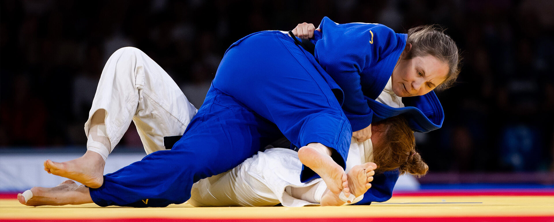Two female judoka grappling on the floor