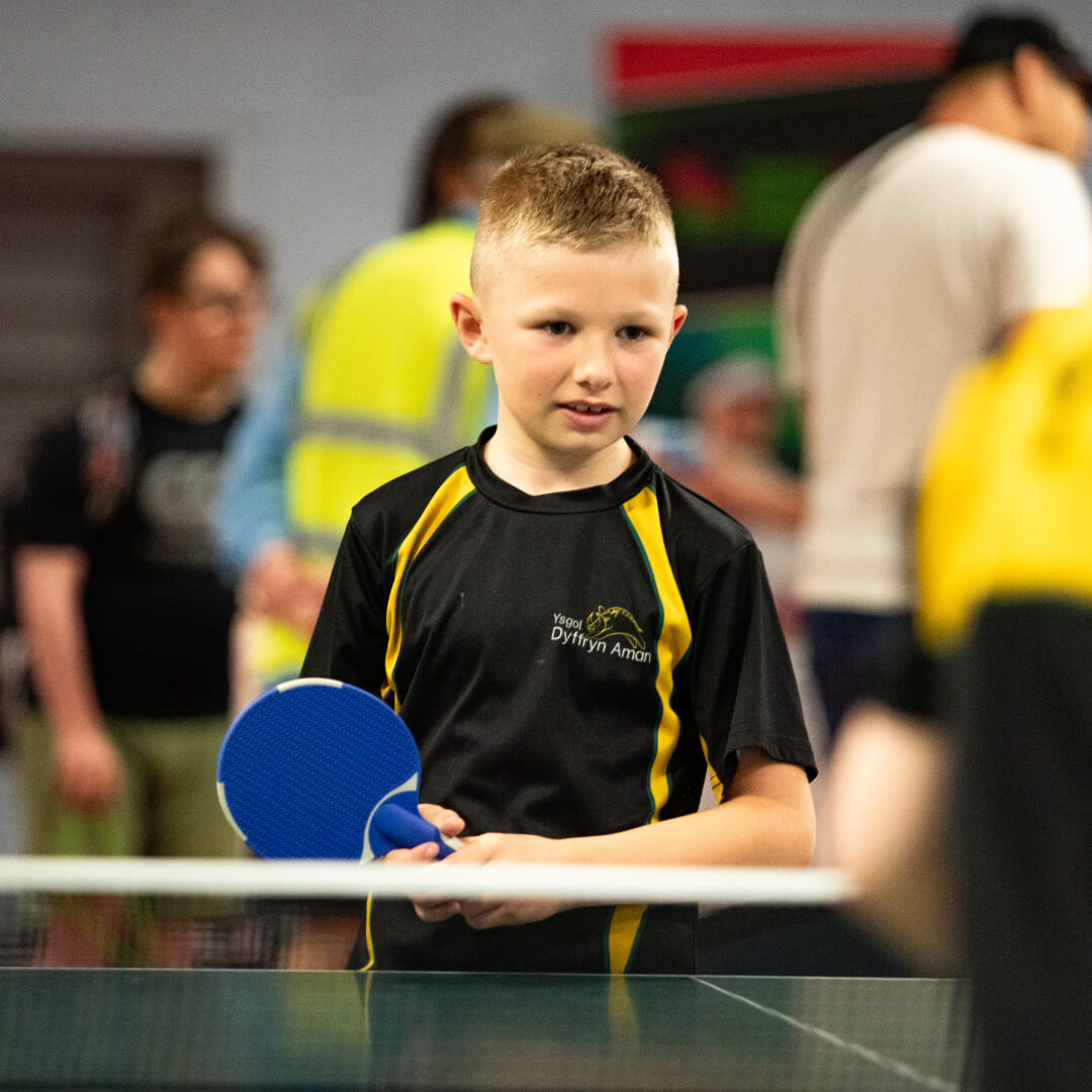 A young boy tries table tennis at insport Series: Swansea 2025