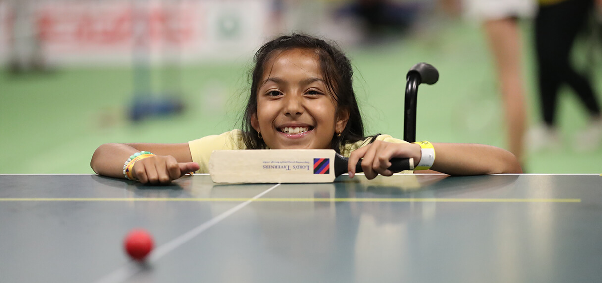 A young female chair user plays table cricket at insport Series Swansea 2023